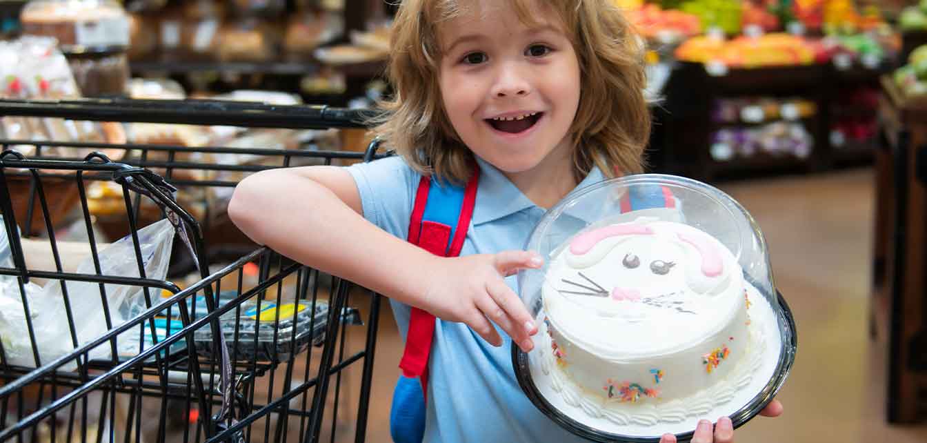 Child smiling while holding a cake in a grocery store
